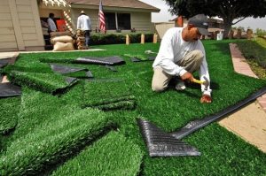 Image of an man doing Artificial turf is a surface of synthetic fibers made to look like natural grass.